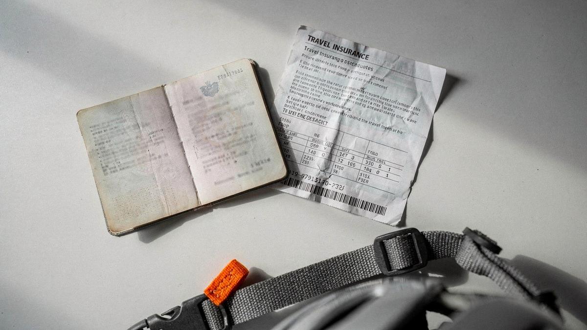 Passport, boarding pass and printed travel insurance laid out on a desk beside a ski helmet